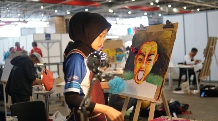 Nur Amiratul Farahin painting a portrait at an easel while competing at the International Abilympics in Metz, France.