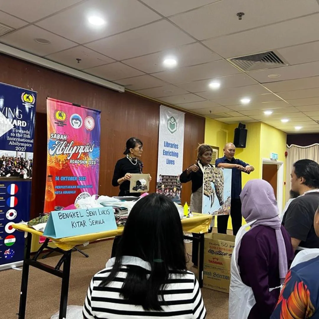 Facilitators hold up recycled-art paintings at the Sabah Abilympics Roadshow workshop at the Sabah State Library, Kota Kinabalu, October 2023.