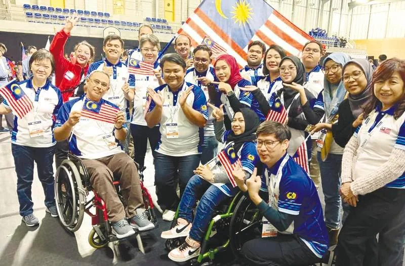 Malaysia's Abilympics delegation holding Malaysian flags at the 10th International Abilympics in Metz, France.