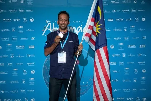 Haymasuthan Periasamy holding his gold medal and the Malaysian flag at the International Abilympics.