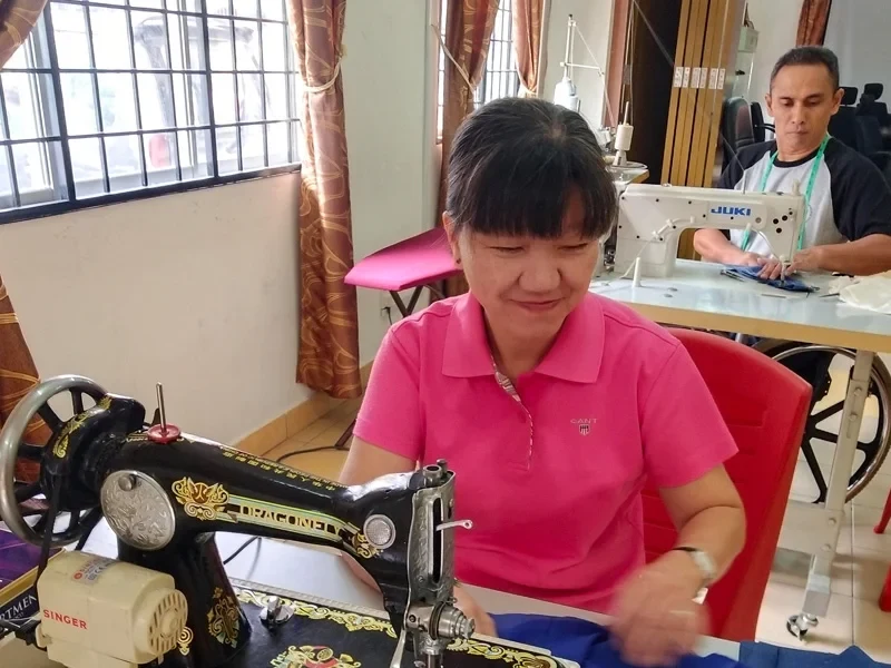 Malaysian competitor at work on dressmaking at Abilympics competition.