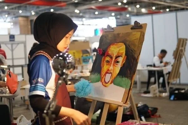 Nur Amiratul Farahin concentrating over her artwork while competing in Painting & Waste Reuse at the 10th International Abilympics.